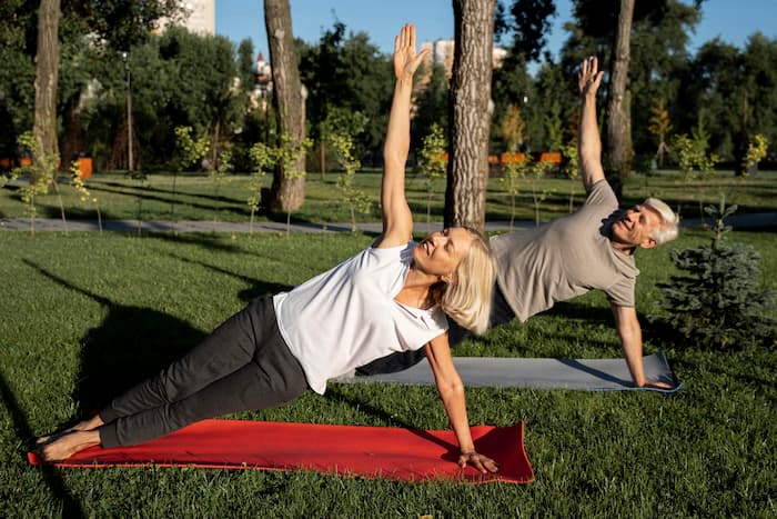 side-view-elder-couple-doing-yoga-outdoors